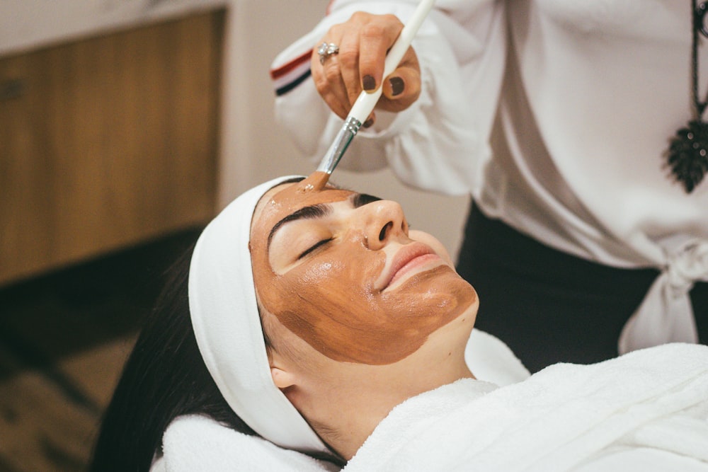 Especialista aplicando una mascarilla facial durante un tratamiento de spa